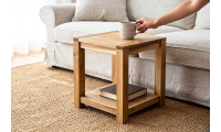 Petit meuble bas écologique en bois massif d'hévéa naturel, avec tablette inférieure, posé près d'un canapé; tasse sur le platea